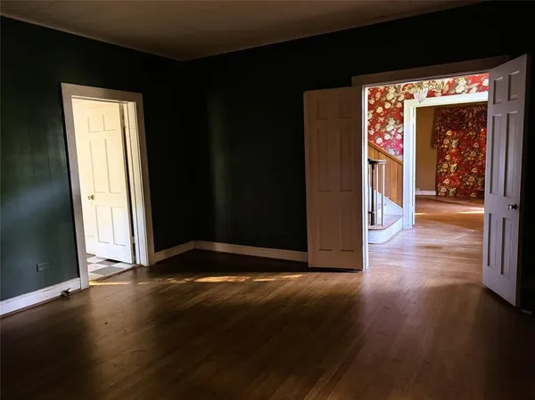 a view of an empty room with a window and wooden floor
