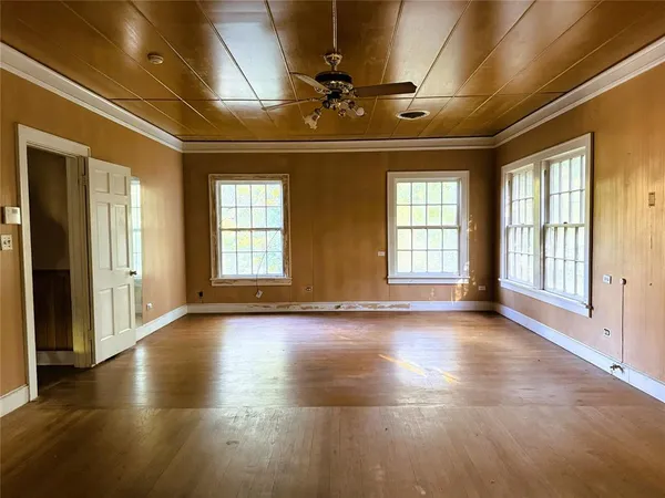 a view of empty room with wooden floor and fan