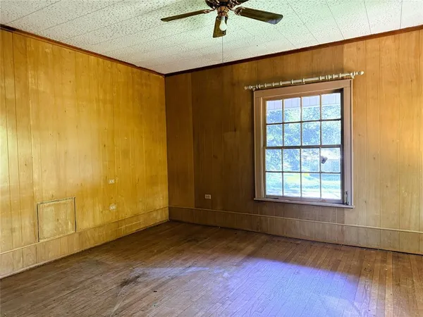an empty room with ceiling fan and windows