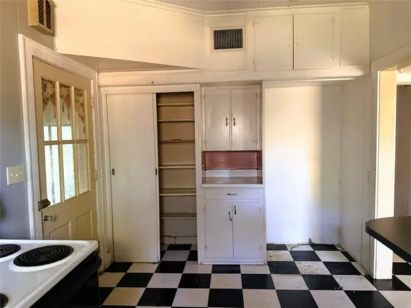 a kitchen with a checkered floor and white cabinets