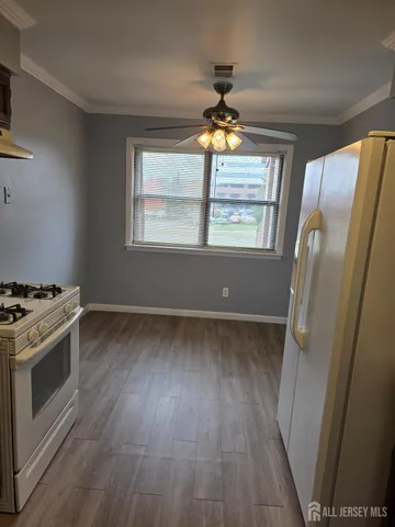 an empty room with wooden floor a ceiling fan and windows