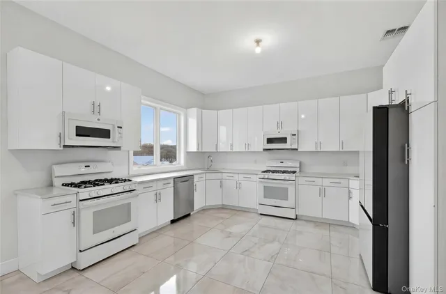 a kitchen with stainless steel appliances granite countertop a stove top oven a sink dishwasher and a refrigerator