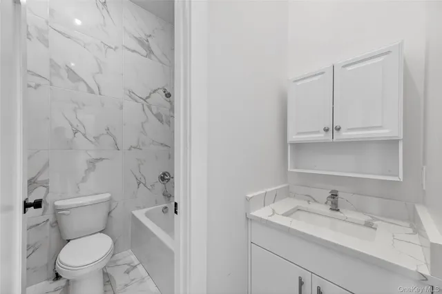 a bathroom with a granite countertop toilet a sink and a bathtub