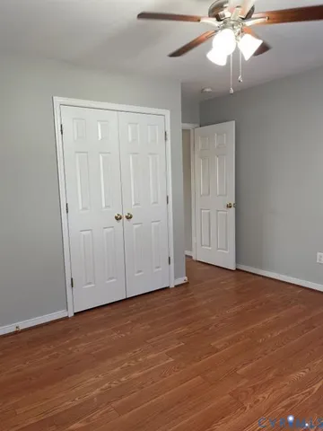 an empty room with wooden floor fan and windows