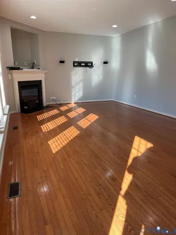 a view of empty room with wooden floor and fireplace