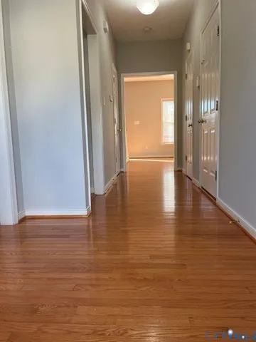 a view of an empty room with wooden floor and a window