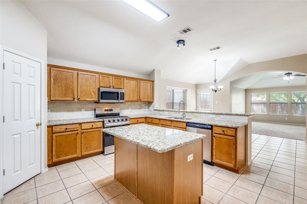 1117 Red Hawk Drive Frisco, TX 75033 - Photo 6 of 31 a kitchen with stainless steel appliances granite countertop a stove a sink and a microwave