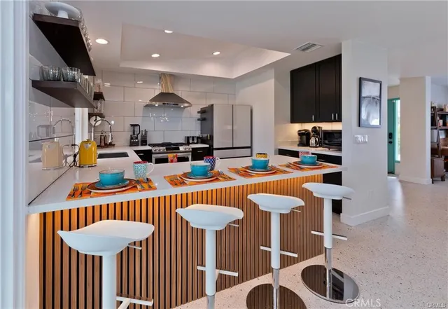 a kitchen with stainless steel appliances granite countertop a sink a stove a dining table and chairs