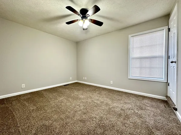 an empty room with a window and a fan