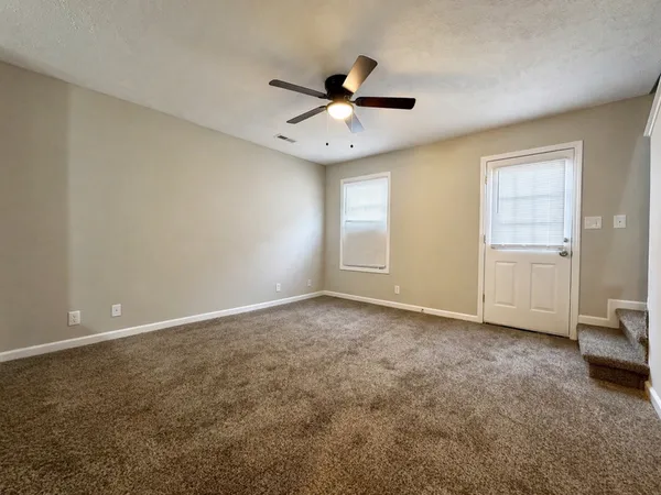 an empty room with windows and ceiling fan