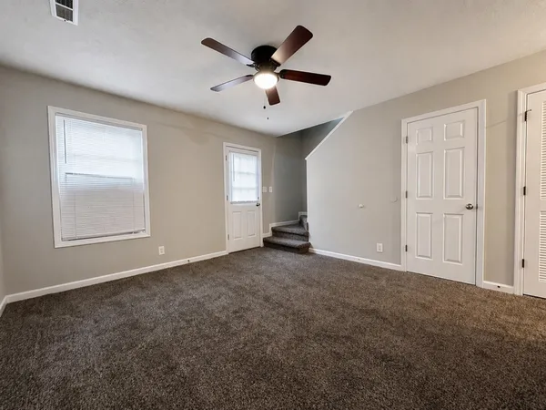 an empty room with windows and ceiling fan