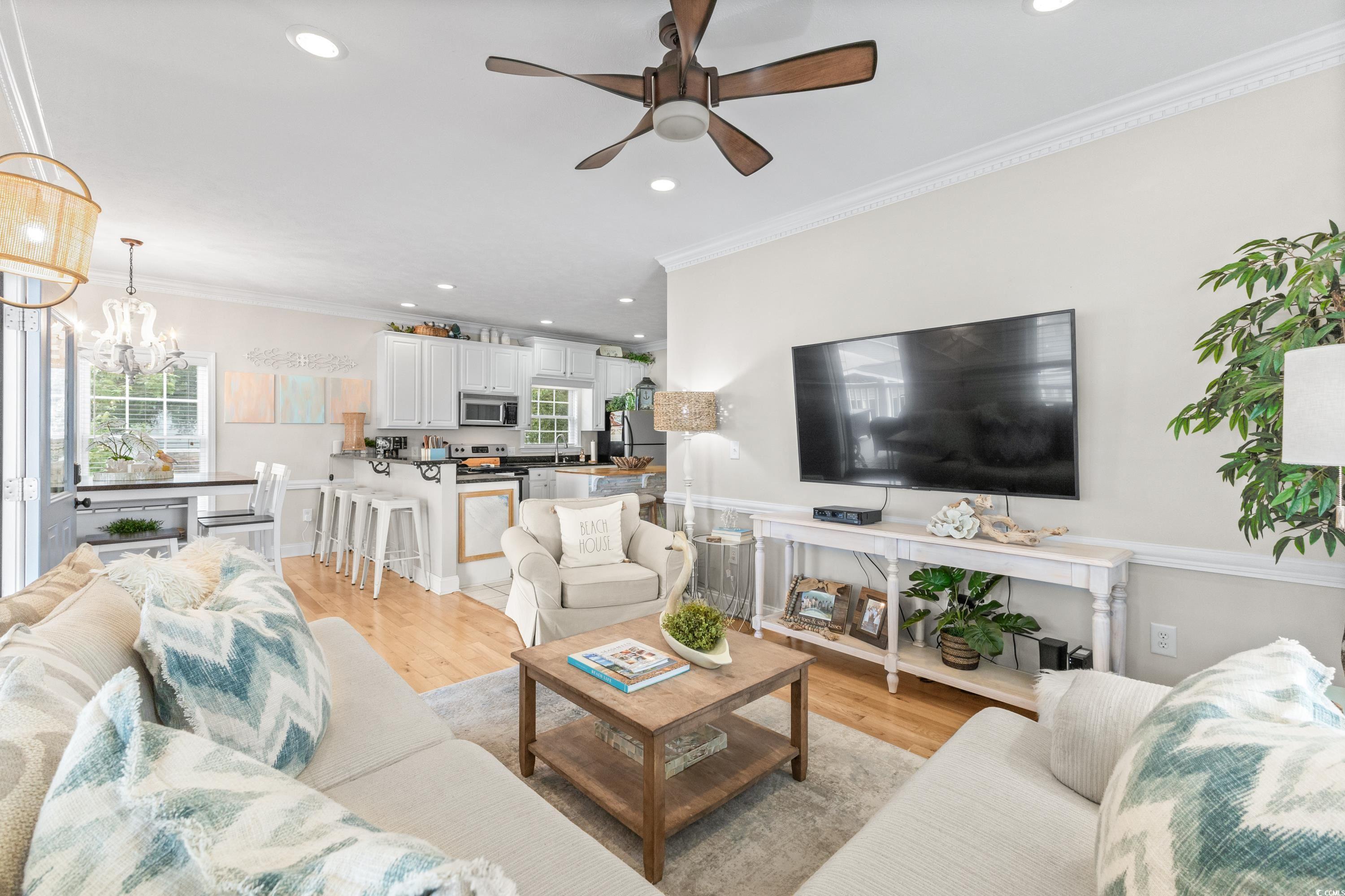 6001-1846a South Kings Highway Myrtle Beach, SC 29575 - Photo 15 of 40 Living room with light hardwood / wood-style floors, ornamental molding, a healthy amount of sunlight, and ceiling fan with notable chandelier