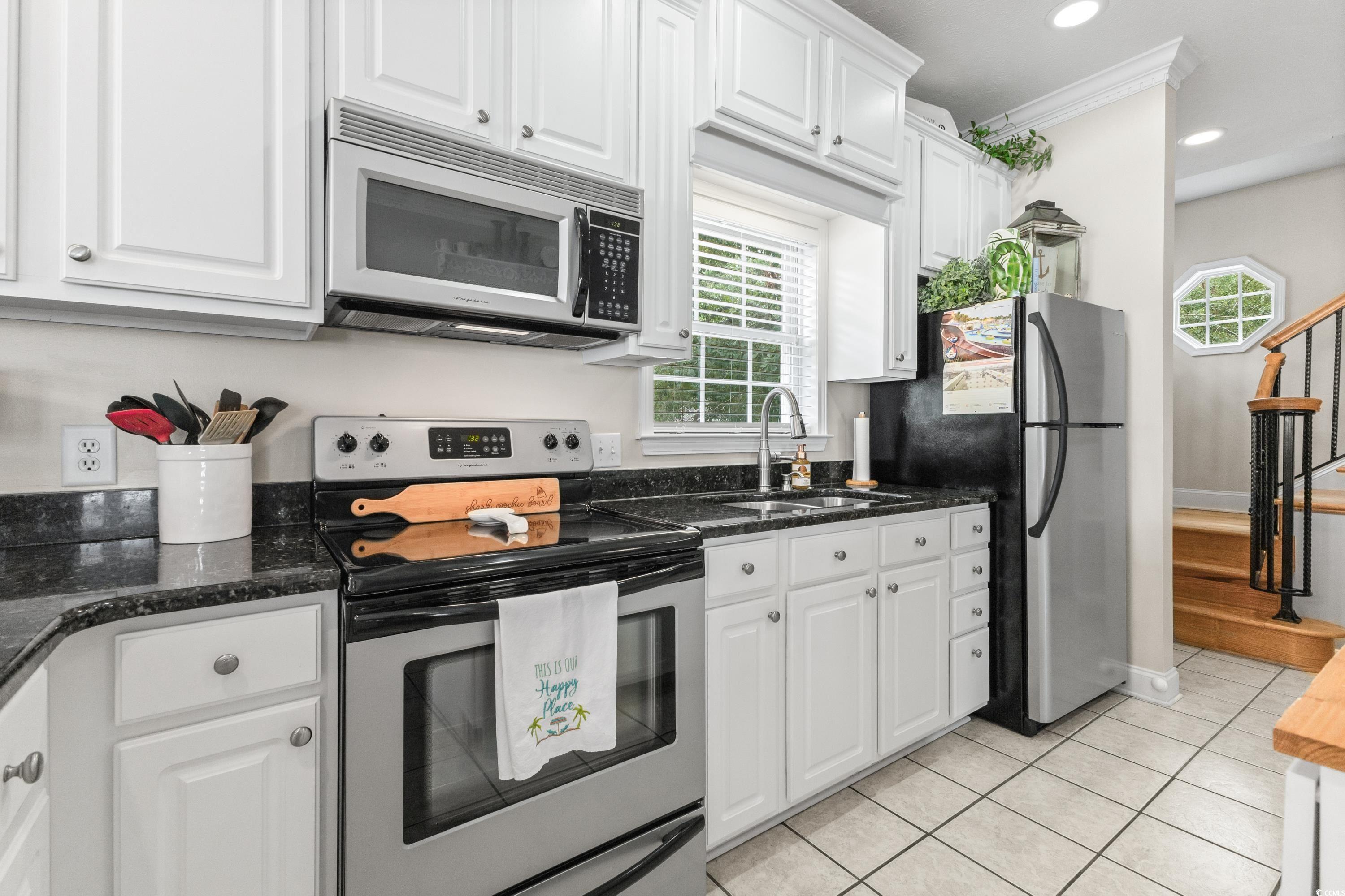 6001-1846a South Kings Highway Myrtle Beach, SC 29575 - Photo 23 of 40 Kitchen with white cabinetry, stainless steel appliances, ornamental molding, sink, and dark stone countertops