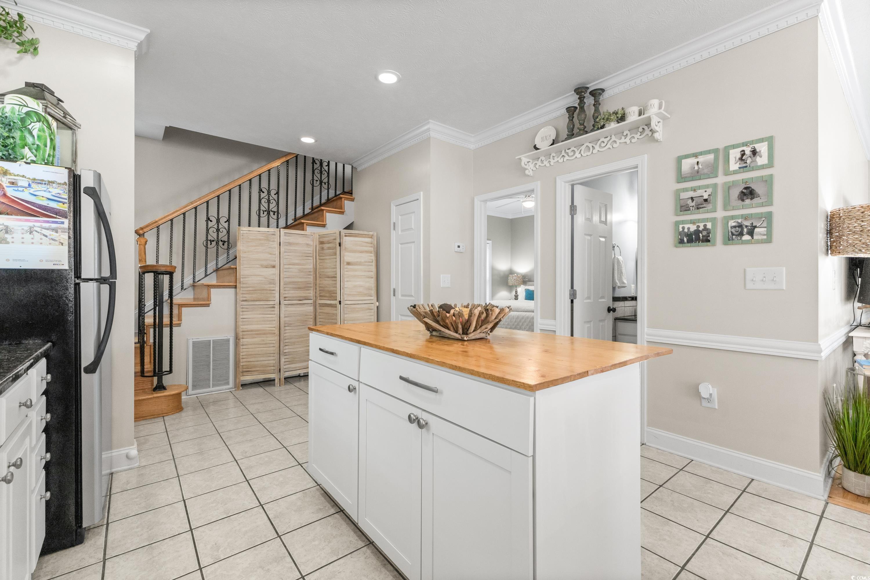 6001-1846a South Kings Highway Myrtle Beach, SC 29575 - Photo 24 of 40 Kitchen featuring crown molding, white cabinetry, stainless steel refrigerator, and light tile patterned floors