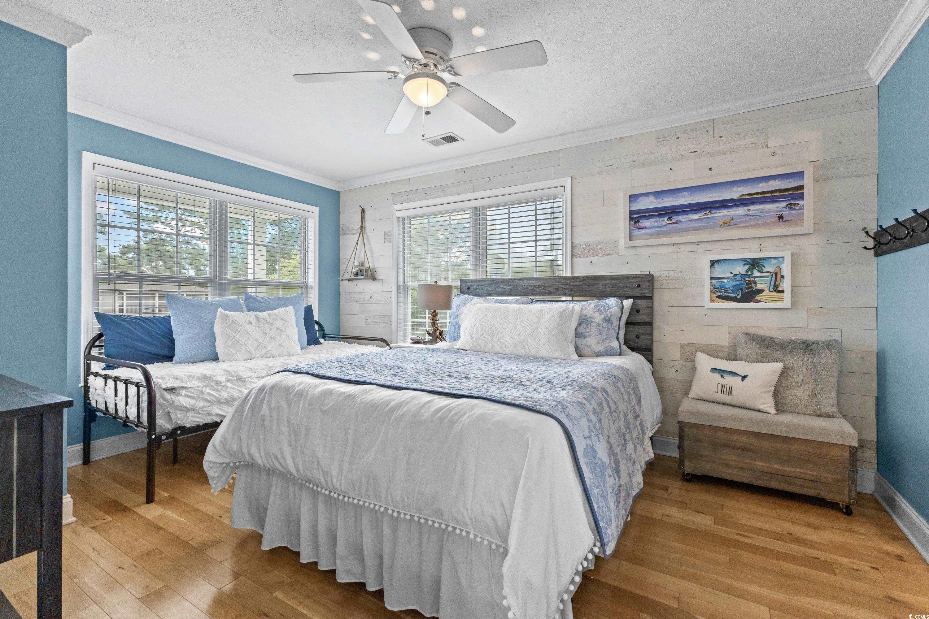 6001-1846a South Kings Highway Myrtle Beach, SC 29575 - Photo 35 of 40 Bedroom featuring ceiling fan, wood walls, ornamental molding, light hardwood / wood-style floors, and a textured ceiling