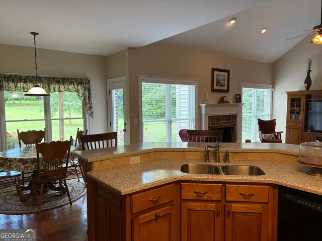 a kitchen with a sink a counter top space and living room view