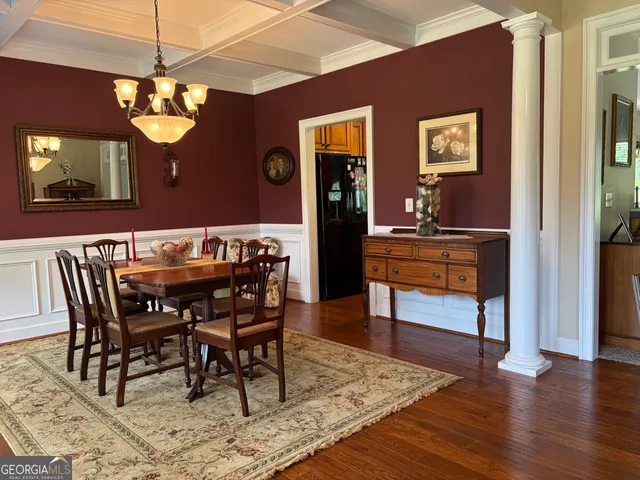 a dining room with wooden floor a chandelier a wooden table and chairs