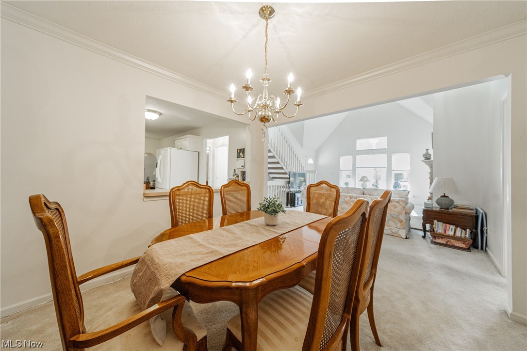 4220 Castle Ridge Akron, OH 44321 - Photo 7 of 35 Carpeted dining room featuring lofted ceiling, ornamental molding, and a notable chandelier