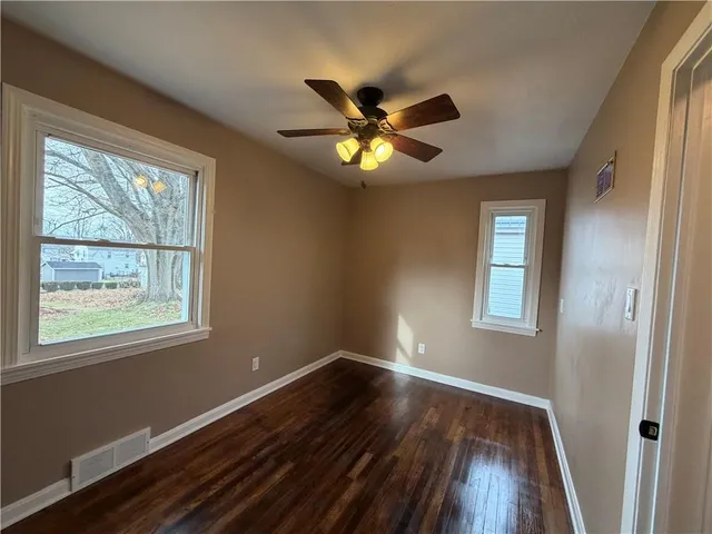a view of an empty room with window and wooden floor