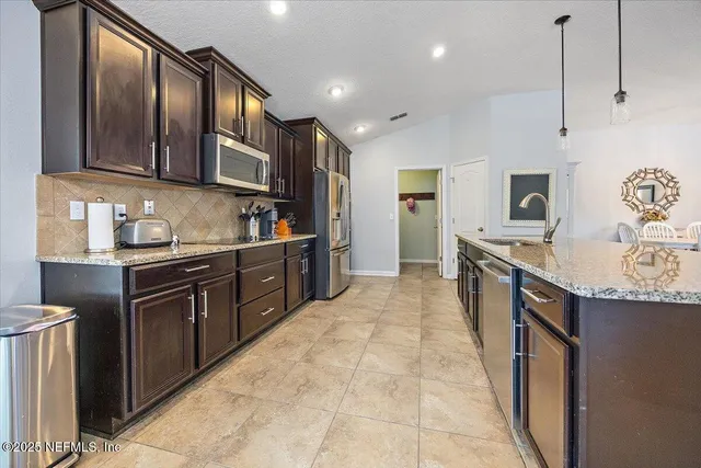 a large kitchen with stainless steel appliances granite countertop a sink stove and refrigerator