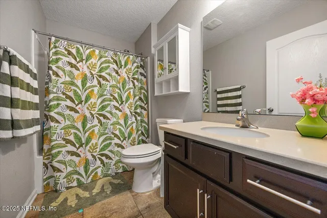 a bathroom with a sink a toilet a mirror and shower curtain