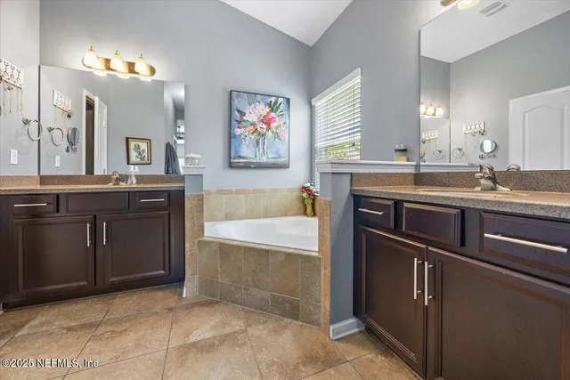 a spacious bathroom with a granite countertop sink a mirror and a bathtub
