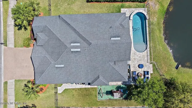 an aerial view of a house with swimming pool and large trees