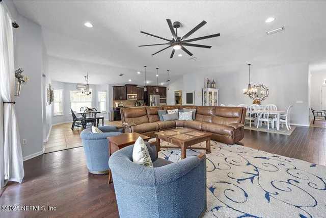 a living room with furniture kitchen view and a wooden floor