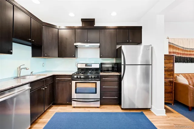 a kitchen with stainless steel appliances granite countertop a refrigerator stove top oven and sink