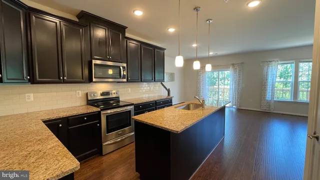 a kitchen with stainless steel appliances granite countertop hardwood floor sink stove dining table and chairs