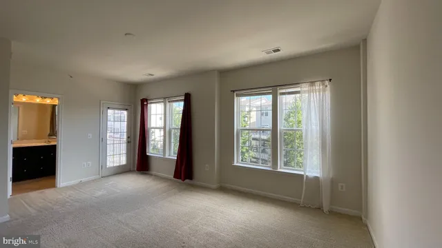 a view of an empty room with a window and a kitchen