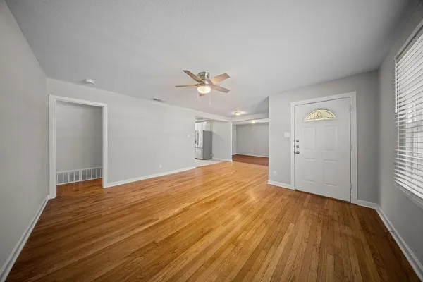 a view of an empty room with wooden floor and a window