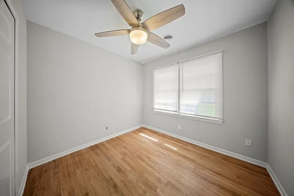 an empty room with a window and a fan