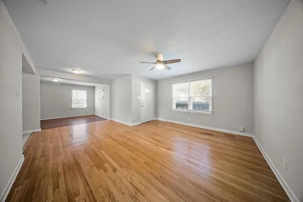 a view of an empty room with a window and wooden floor