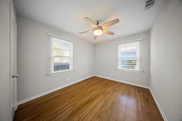 a view of an empty room with a window and wooden floor