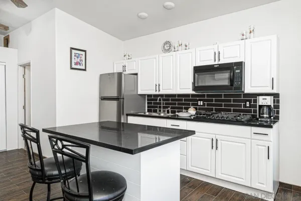 a kitchen with stainless steel appliances a stove a microwave a sink and white cabinets