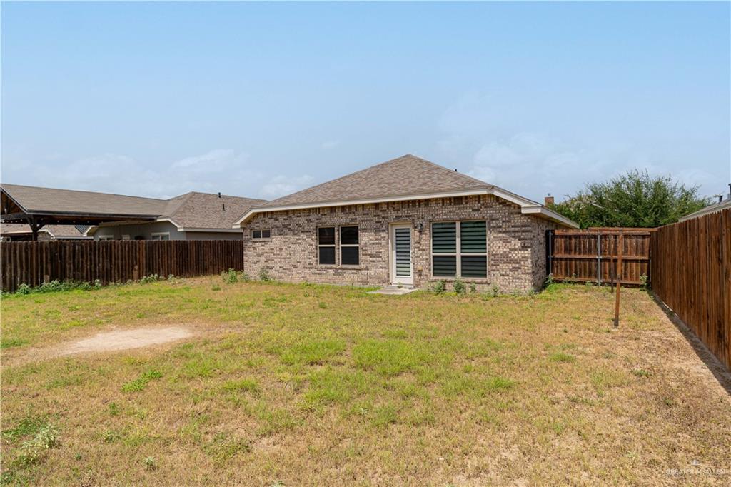412 South Paseo Del Rey Street Mission, TX 78572 - Photo 15 of 15 Back of house with brick siding, a fenced backyard, and a shingled roof