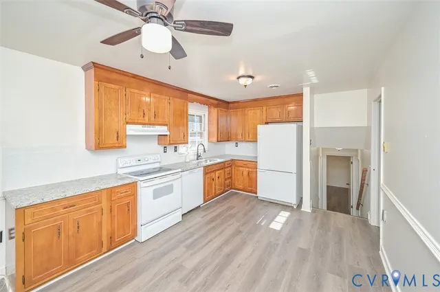 a kitchen with granite countertop a refrigerator a sink dishwasher a stove and white cabinets with wooden floor