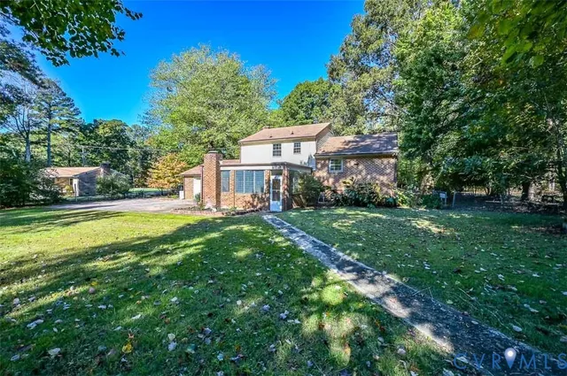 a view of house in front of a big yard with large trees