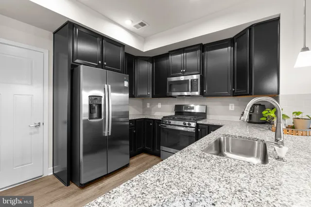 a kitchen with granite countertop a refrigerator sink and stove