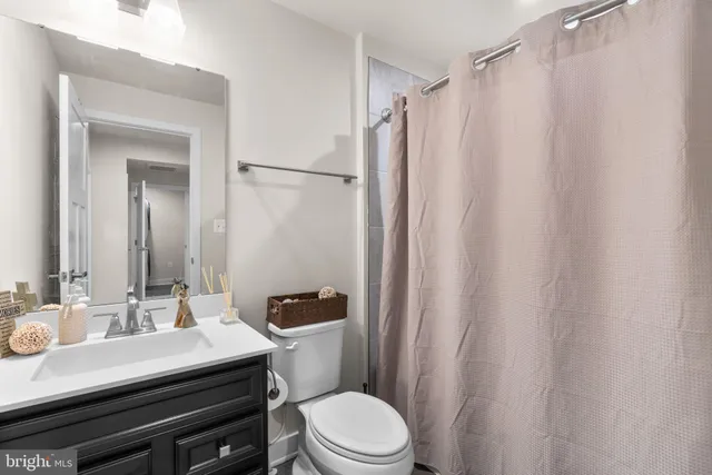 a bathroom with a sink a toilet a mirror and shower curtain
