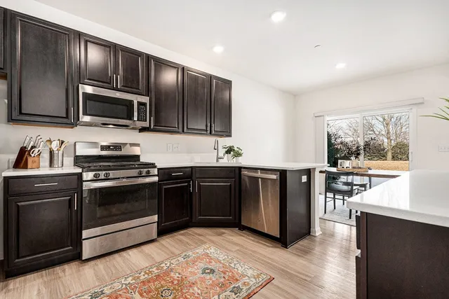 a kitchen with granite countertop wooden cabinets a stove top oven and stainless steel appliances