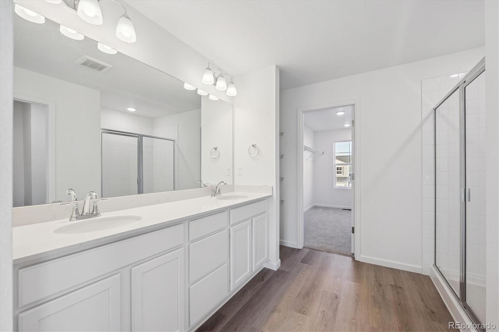 5594 Brangus Drive Windsor, CO 80528 - Photo 18 of 22 a bathroom with a double vanity sink a mirror and a shower