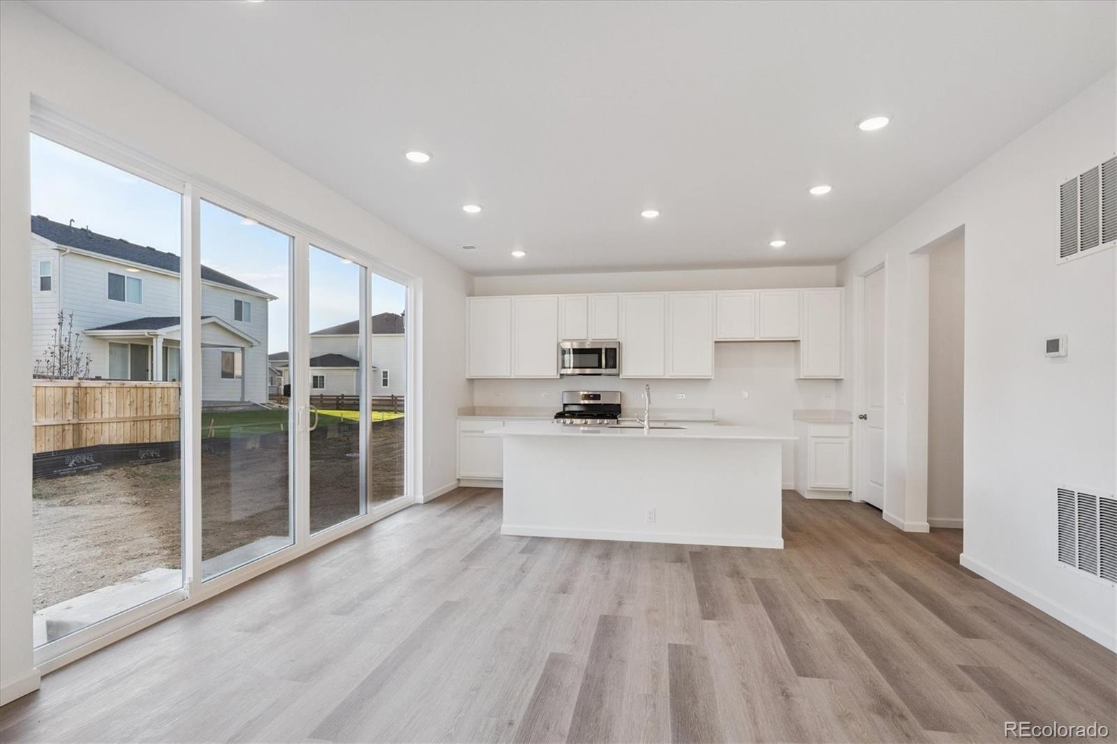 5594 Brangus Drive Windsor, CO 80528 - Photo 8 of 22 a large white kitchen with stainless steel appliances kitchen island a large counter top and a wooden floors