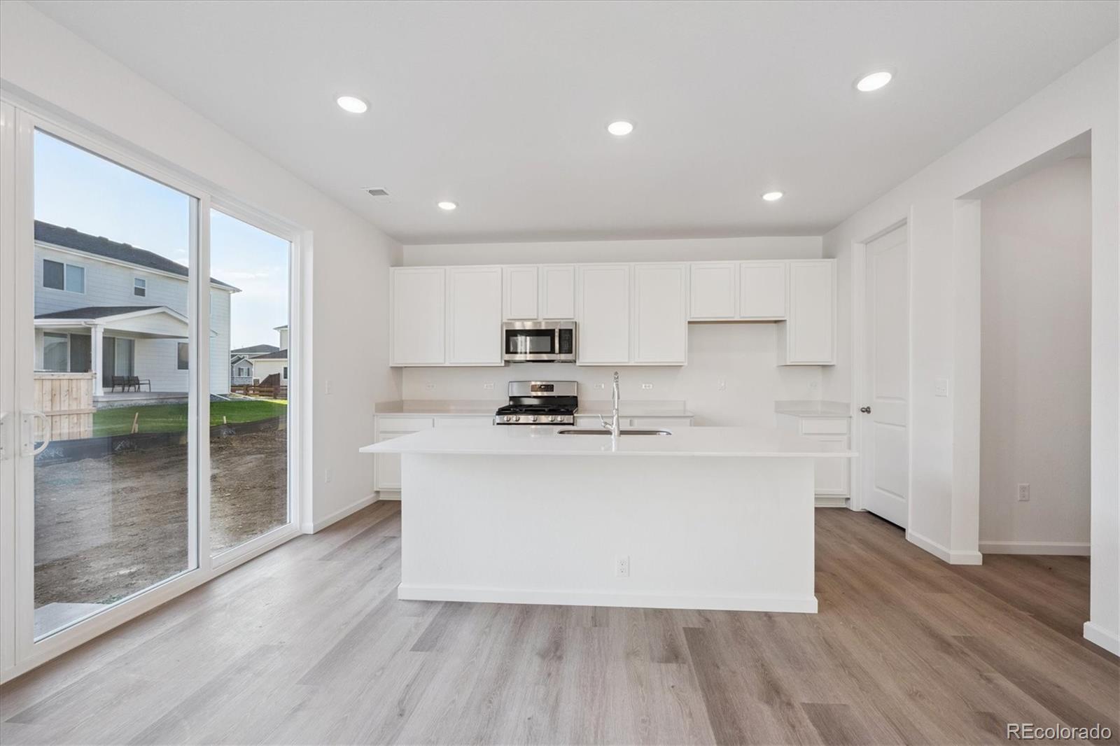 5594 Brangus Drive Windsor, CO 80528 - Photo 9 of 22 a kitchen with stainless steel appliances a sink a stove a refrigerator cabinets and wooden floor