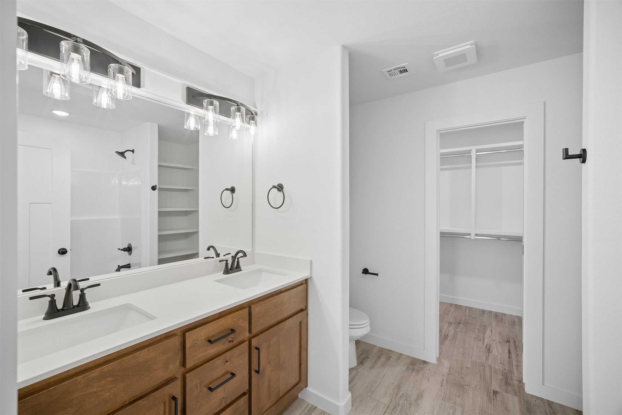 25036 South 4205 Road Inola, OK 74036 - Photo 21 of 30 Dual vanity with a white countertop and wood-finish cabinetry, illuminated by a multi-bulb light fixture