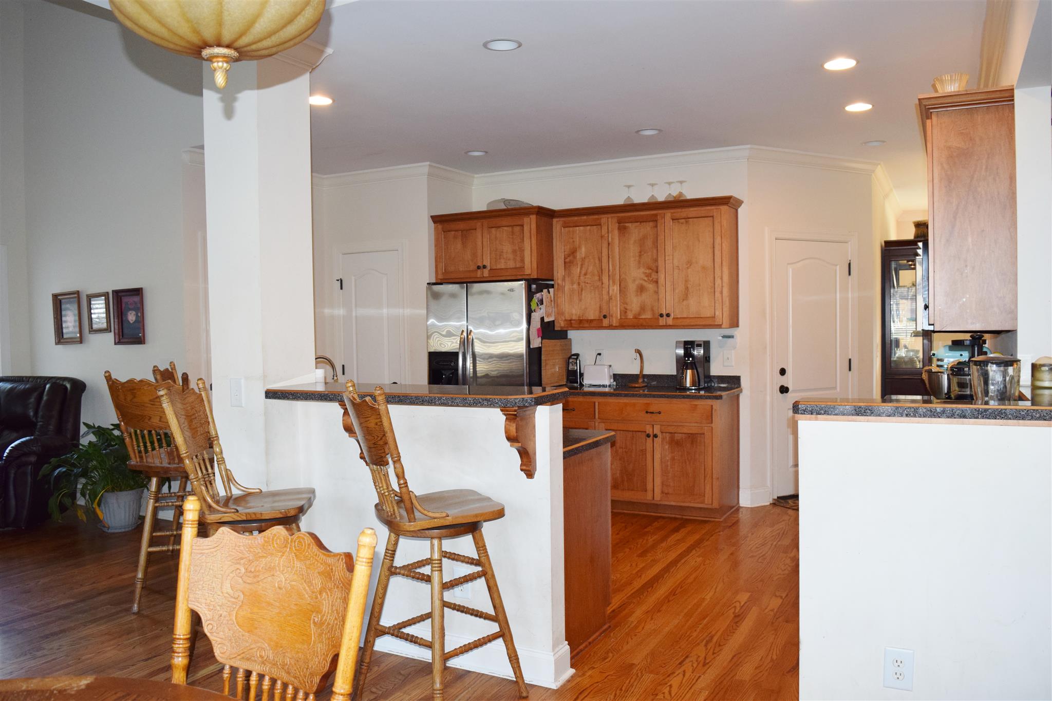 7418 Liberty Road Fairview, TN 37062 - Photo 7 of 18 a kitchen with stainless steel appliances granite countertop a stove top oven a sink a dining table and chairs with wooden floor