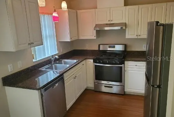 a kitchen with granite countertop a sink stainless steel appliances and cabinets