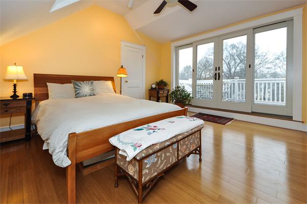 a bedroom with a bed a table and chair with wooden floor