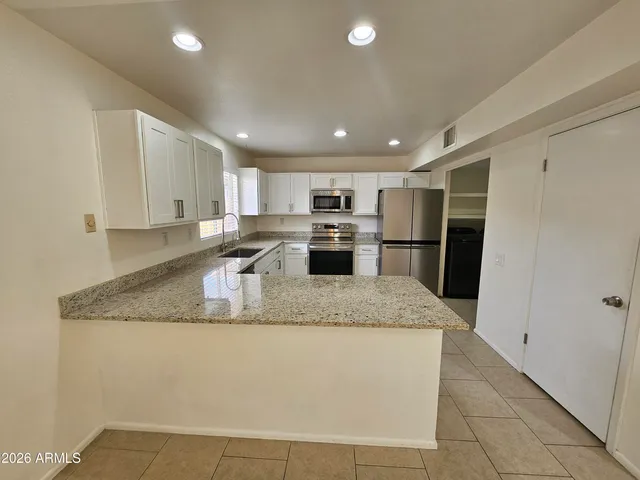 a large kitchen with stainless steel appliances granite countertop a sink refrigerator and cabinets